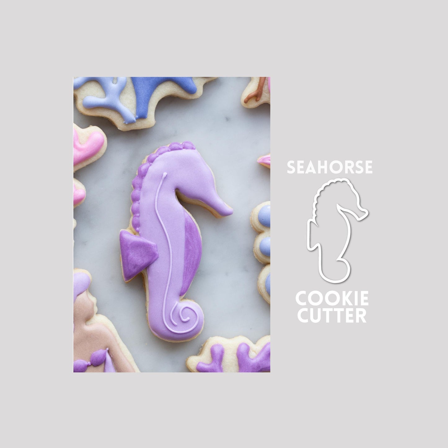 Decorated seahorse sugar cookie next to a seahorse cookie cutter outline on a gray background.