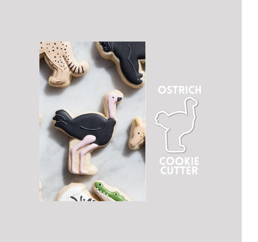 Decorated ostrich sugar cookie next to a ostrich cookie cutter outline on a gray background.