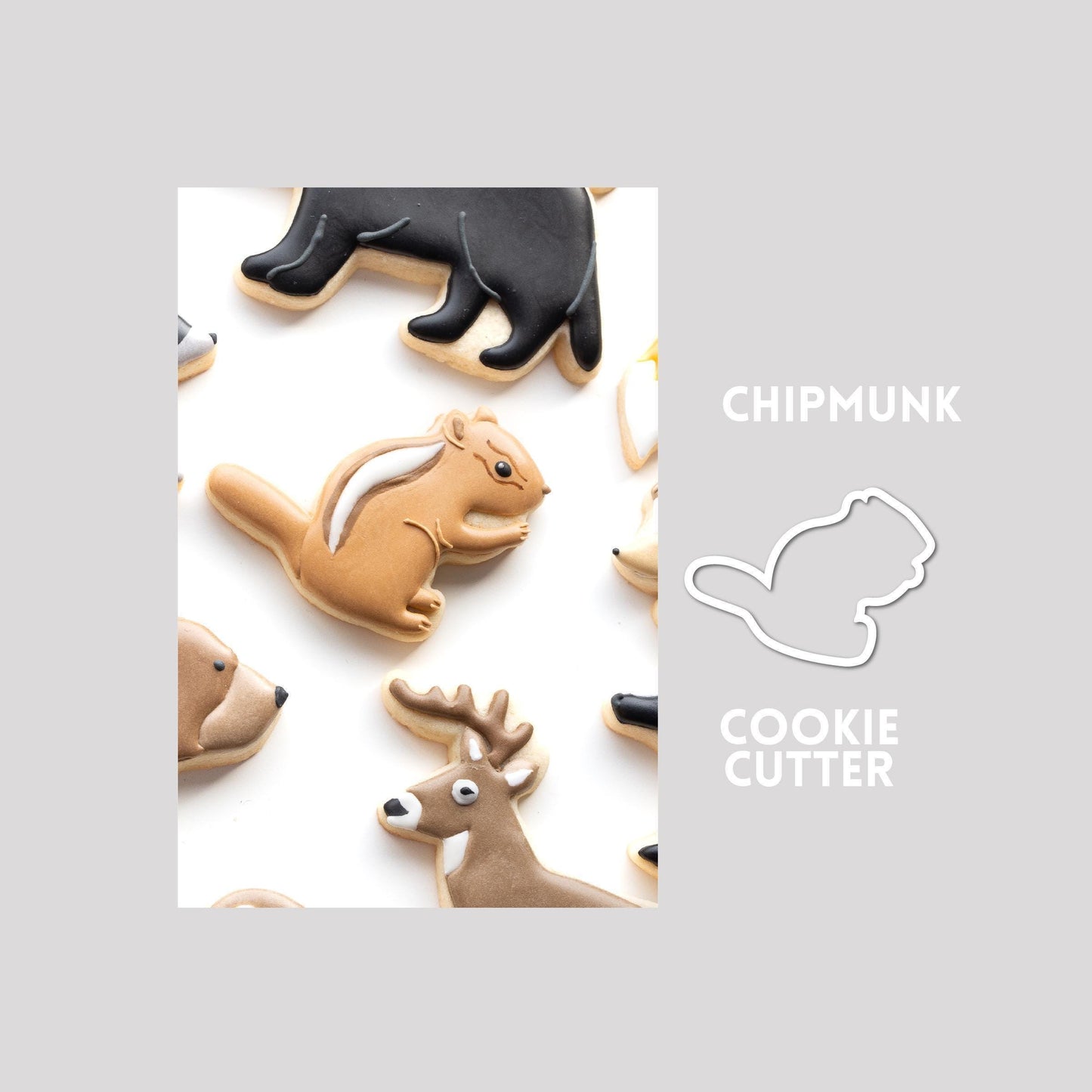 Decorated chipmunk sugar cookie next to a chipmunk cookie cutter outline on a gray background.