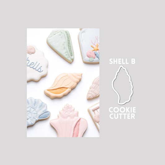 Decorated seashell sugar cookie next to a seashell cookie cutter outline on a gray background.