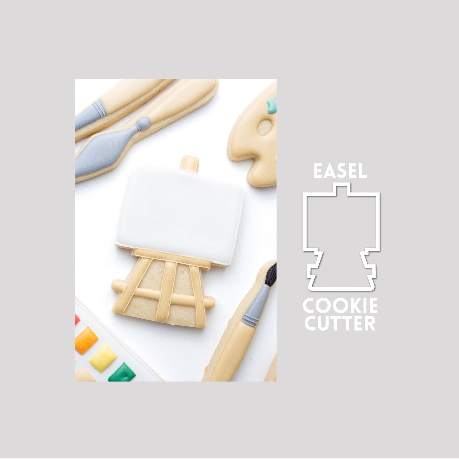 Decorated pain teasel sugar cookie next to a easel cookie cutter outline on a gray background.