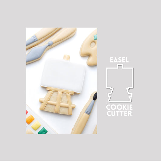 Decorated pain teasel sugar cookie next to a easel cookie cutter outline on a gray background.