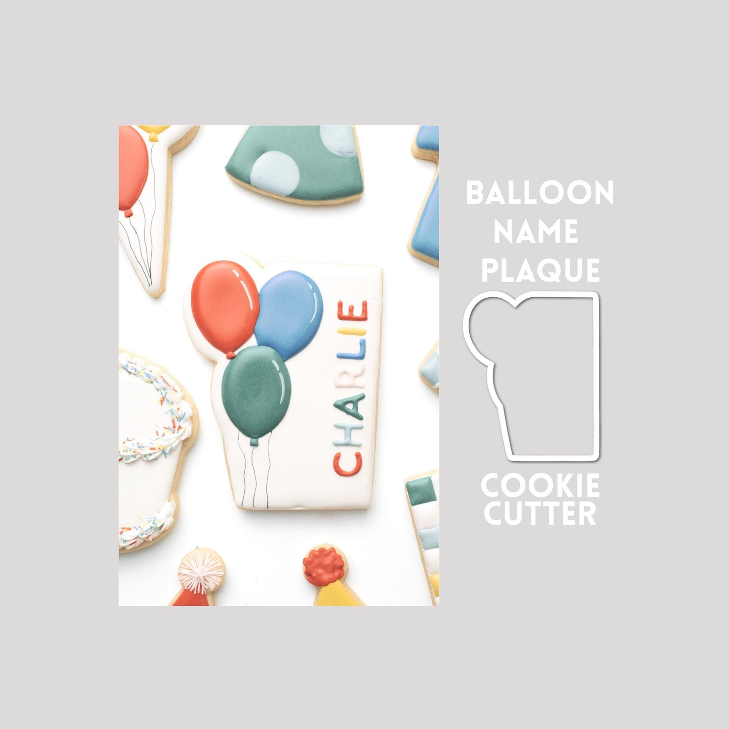 Decorated balloon name plaque sugar cookie next to a balloon name plaque cookie cutter outline on a gray background.