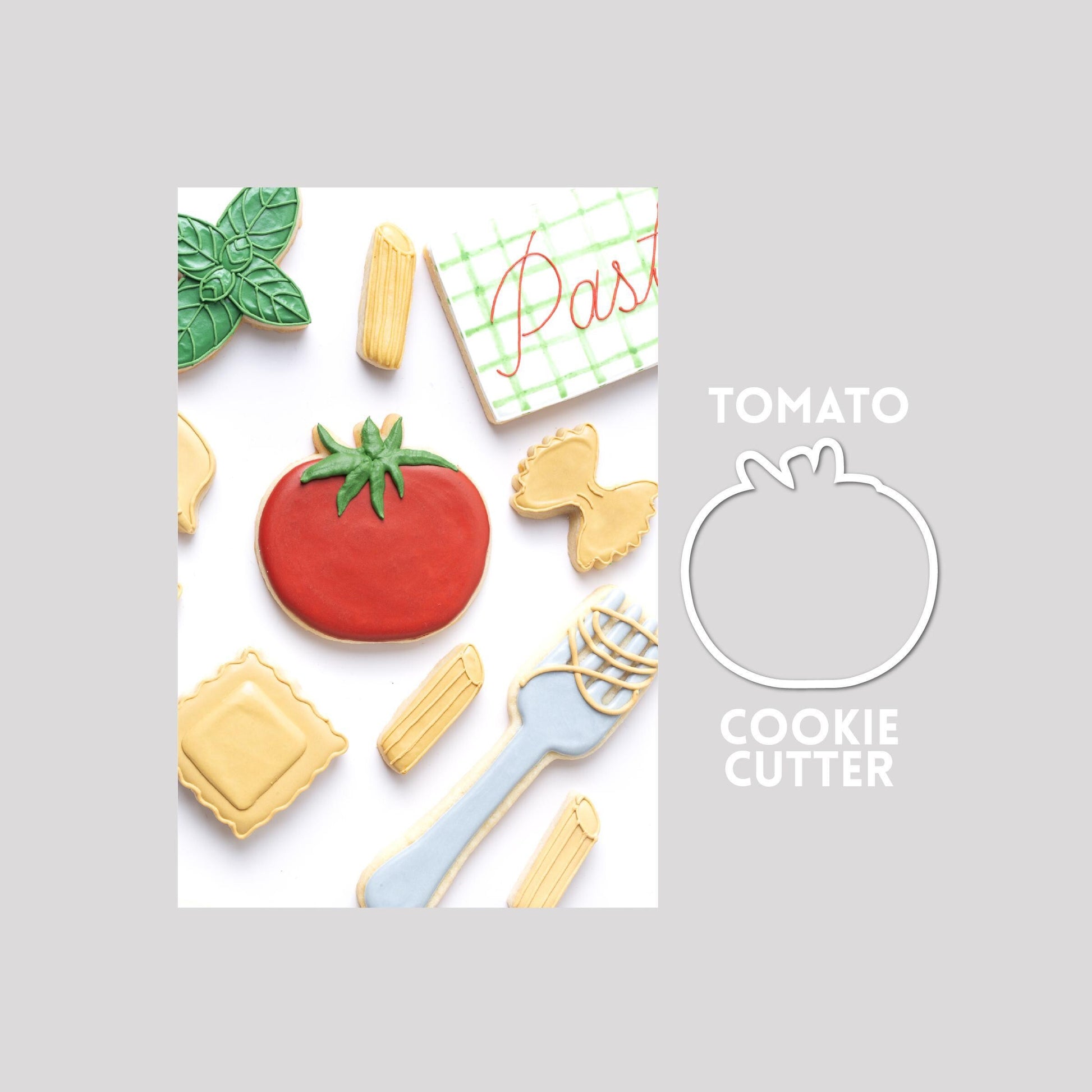Decorated tomato sugar cookie next to a tomato cookie cutter outline on a gray background.