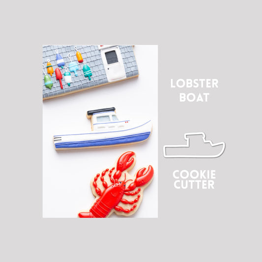 Decorated lobster sugar cookie next to a lobster cookie cutter outline on a gray background.