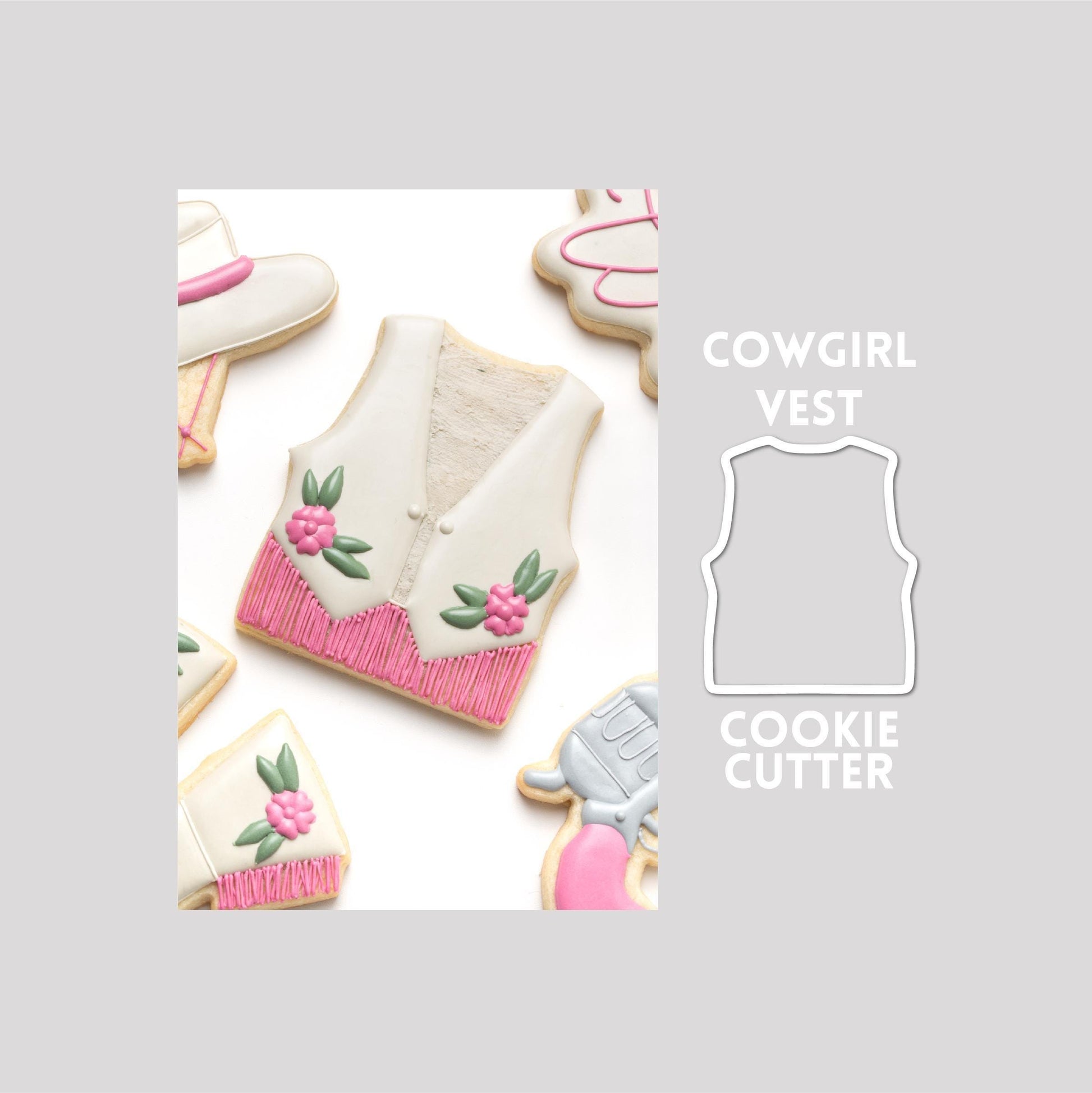 Decorated cow girl vest sugar cookie next to a cow girl vest cookie cutter outline on a gray background.