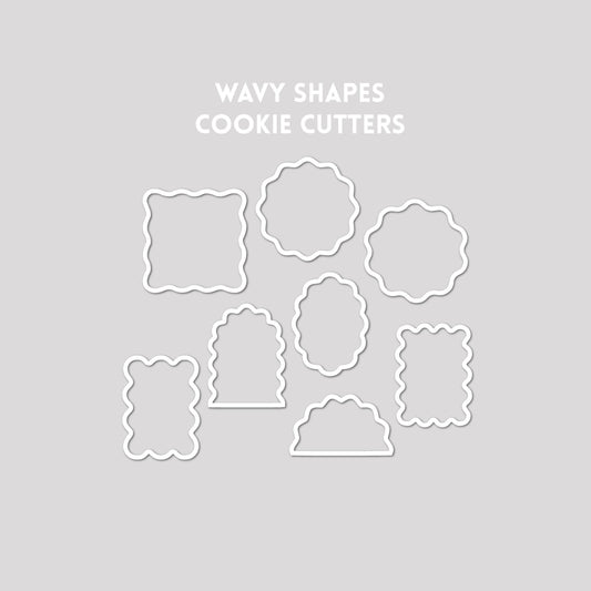 Various wavy shaped cookie cutter outline on a gray background.