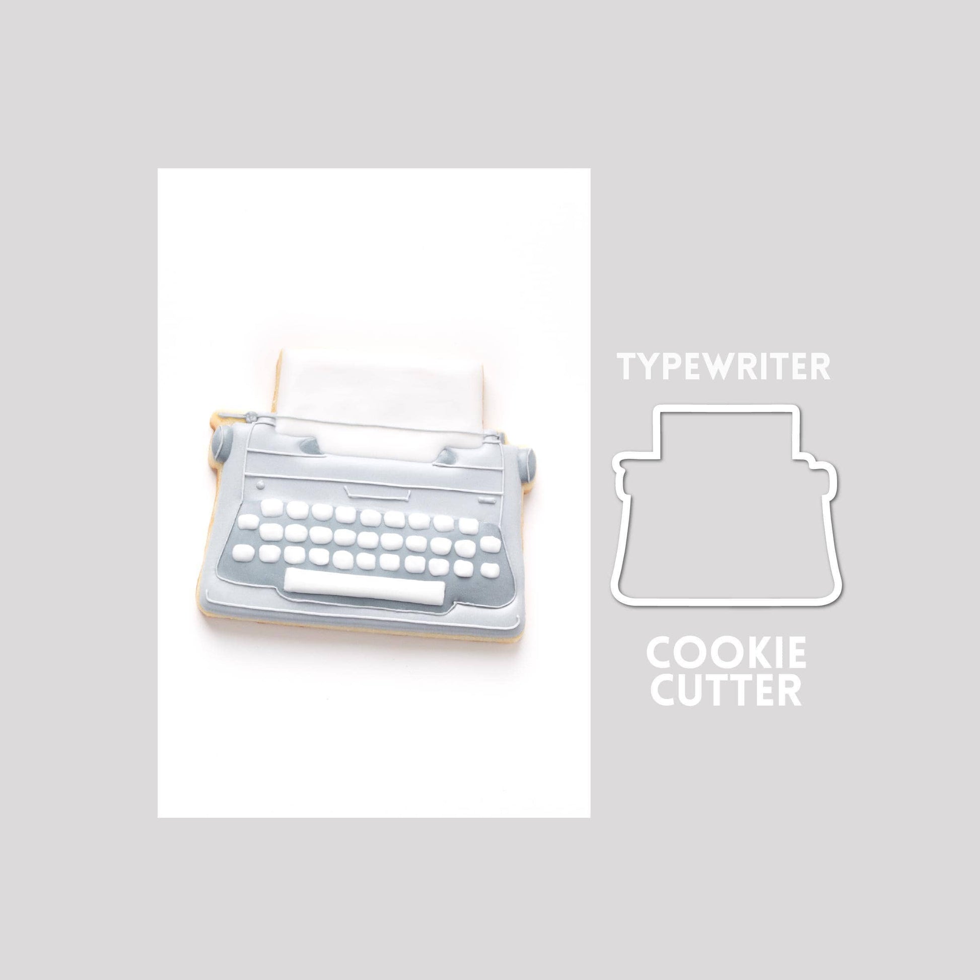 Decorated typewriter sugar cookie next to a typewriter cookie cutter outline on a gray background.