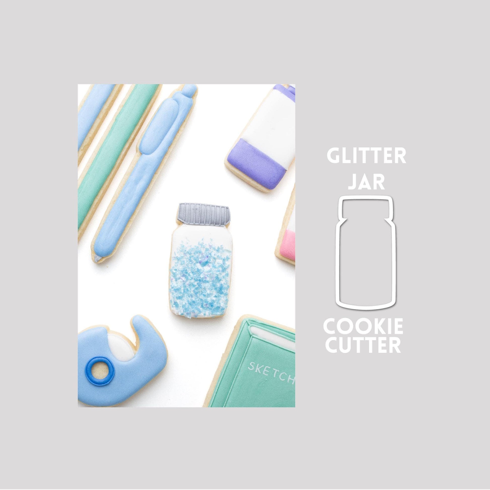Decorated glitter jar sugar cookie next to a glitter jar cookie cutter outline on a gray background.
