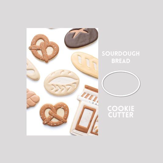 Decorated sourdough bread sugar cookie next to a sourdough bread cookie cutter outline on a gray background.