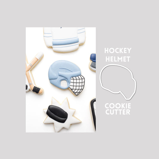 Decorated hockey helmet sugar cookie next to a hockey helmet cookie cutter outline on a gray background.