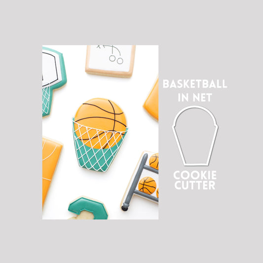 Decorated basketball in net sugar cookie next to a basketball in net cookie cutter outline on a gray background.