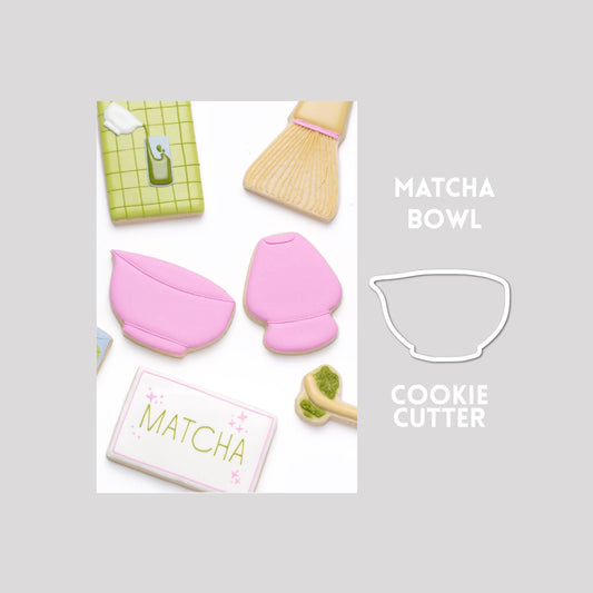 Decorated matcha bowl sugar cookie next to a matcha bowl cookie cutter outline on a gray background.