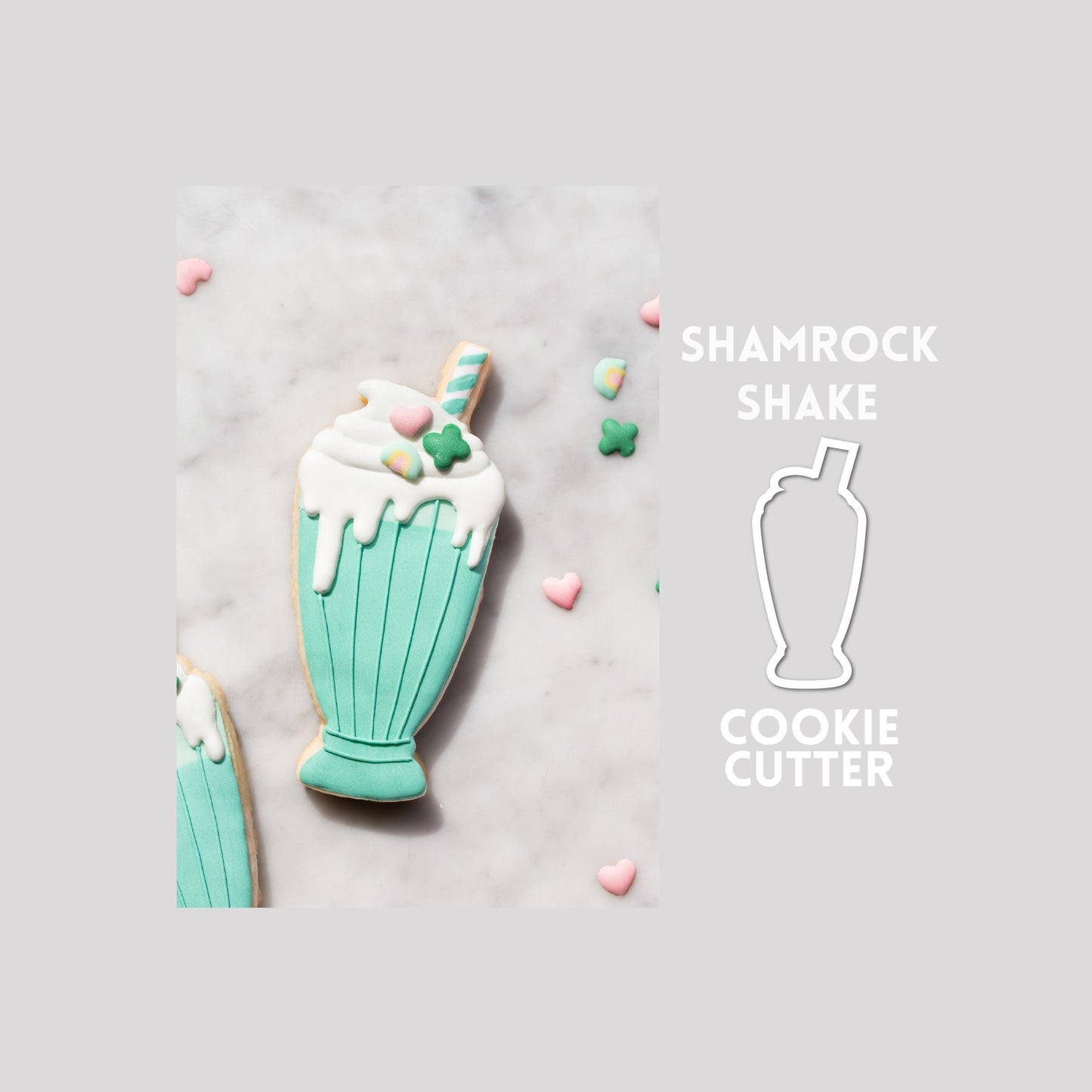 Decorated shamrock shake sugar cookie next to a shamrock shake cookie cutter outline on a gray background.