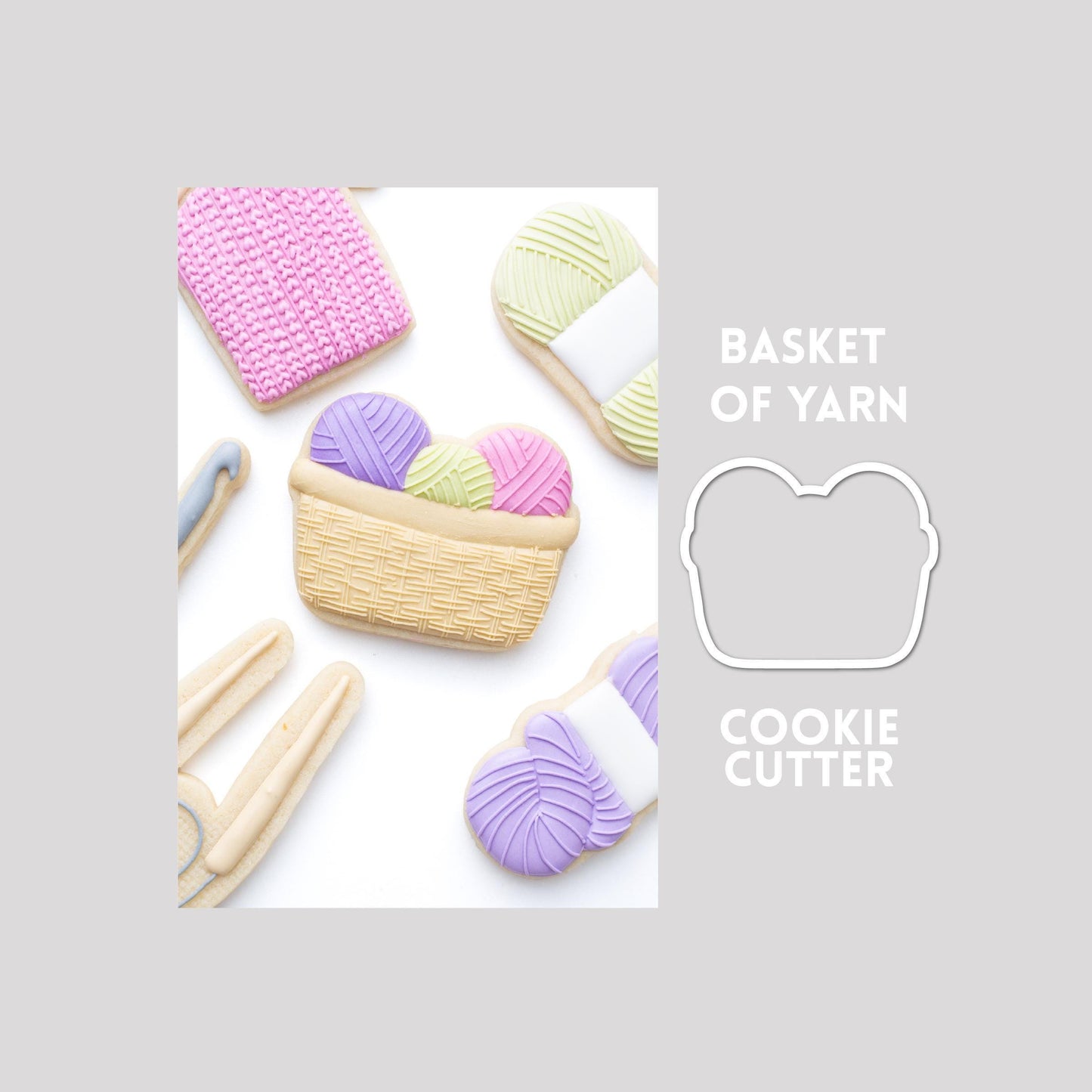 Decorated basket of yarn sugar cookie next to a basket of yarn cookie cutter outline on a gray background.