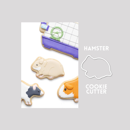 Decorated hamster sugar cookie next to a hamster cookie cutter outline on a gray background.