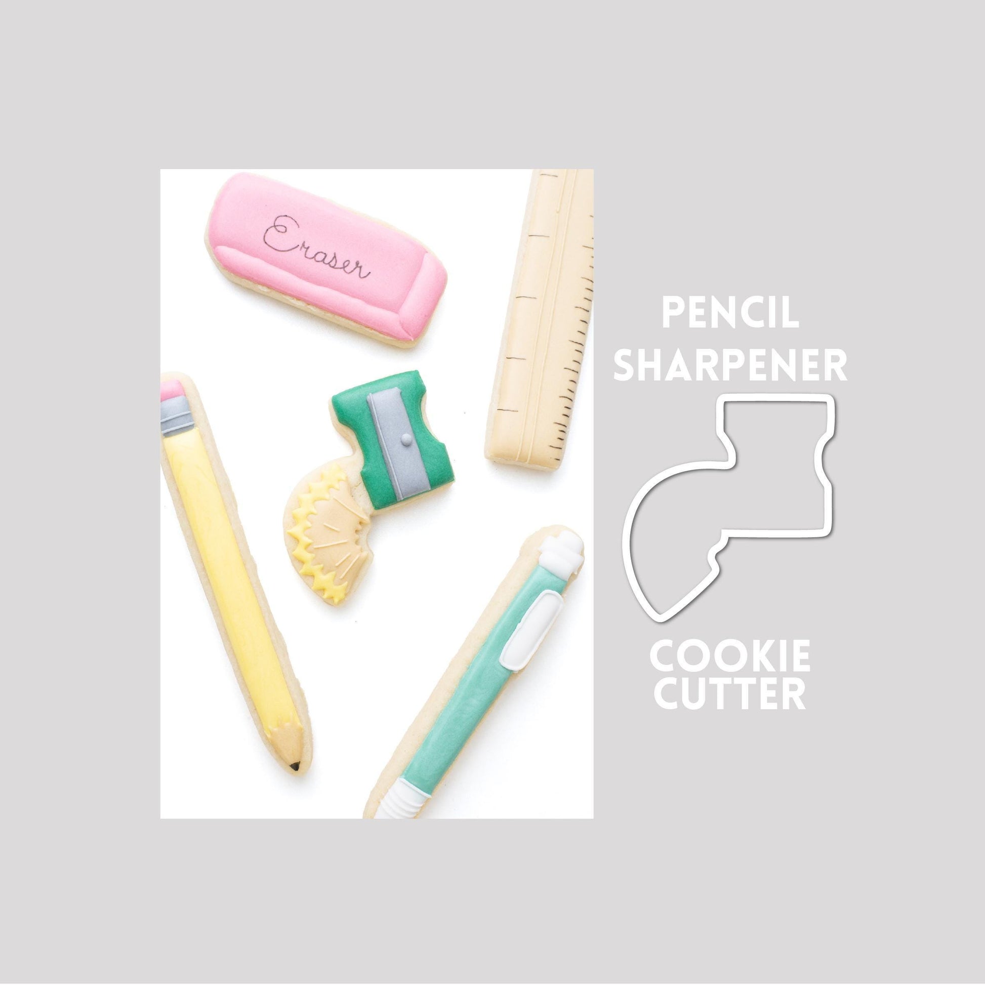 Decorated pencil sharpener sugar cookie next to a pencil sharpener cookie cutter outline on a gray background.