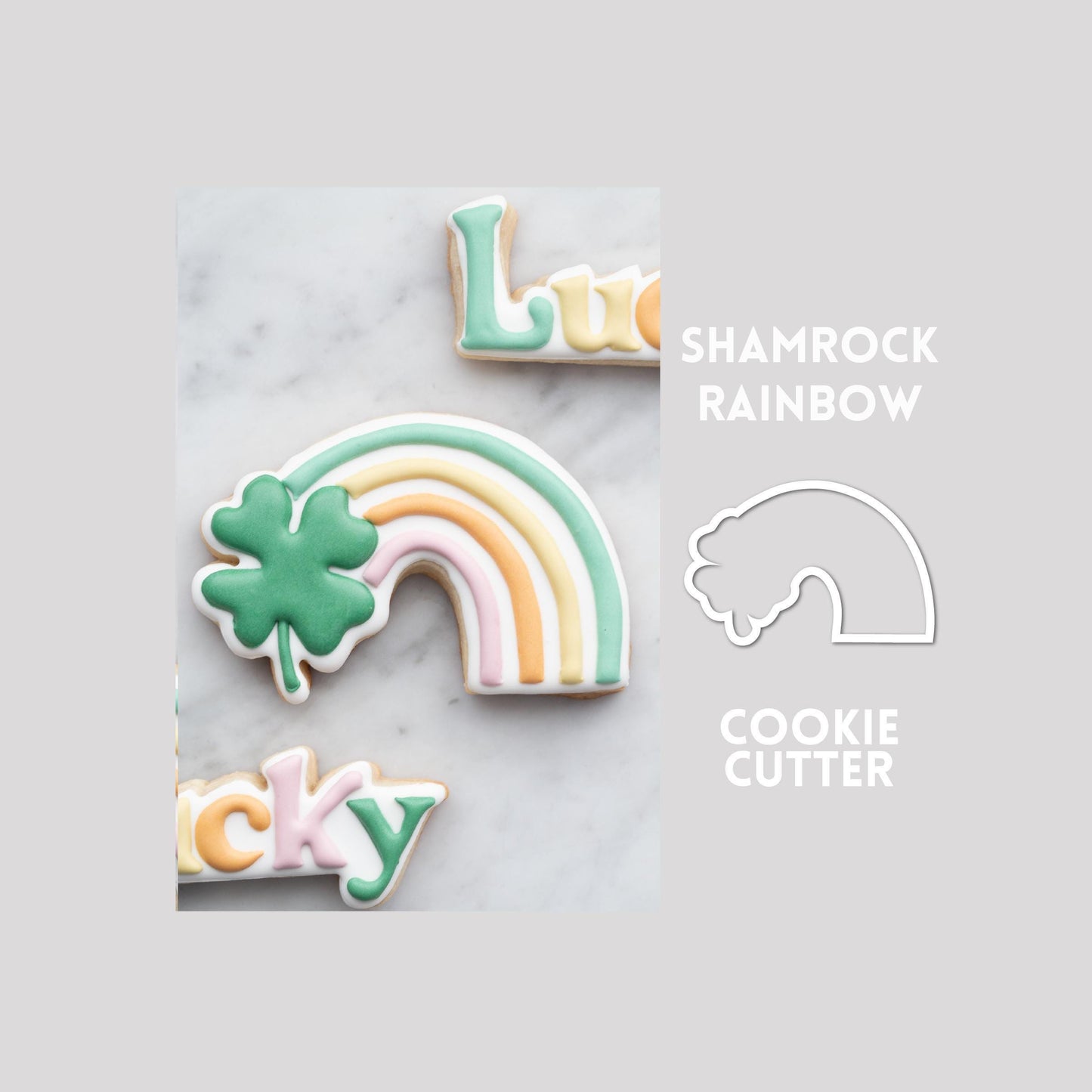 Decorated shamrock rainbow sugar cookie next to a shamrock rainbow cookie cutter outline on a gray background.