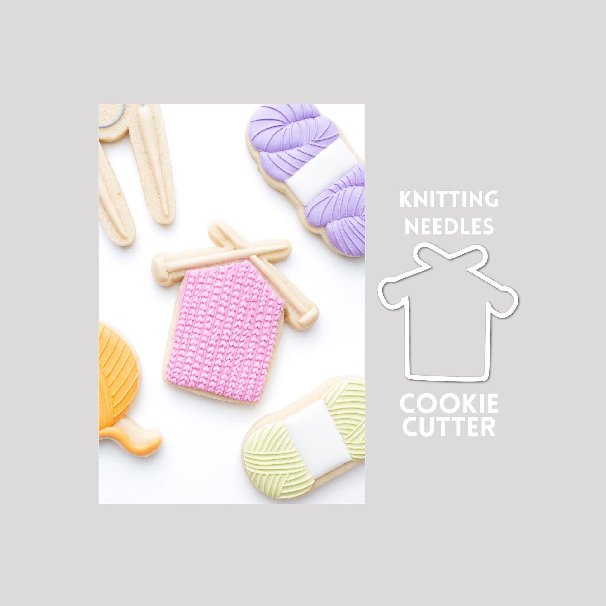 Decorated knitting needles sugar cookie next to a knitting needles cookie cutter outline on a gray background.