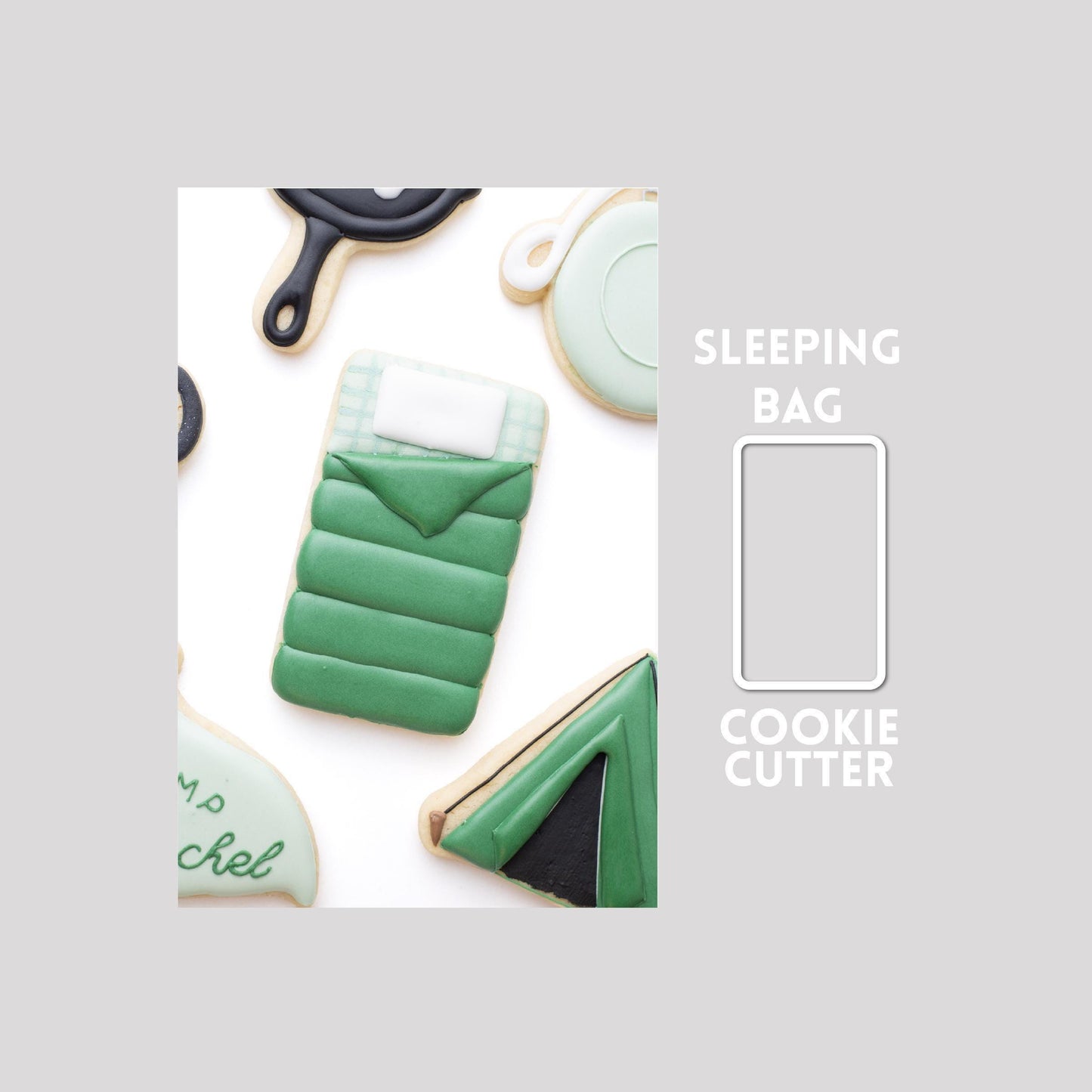 Decorated sleeping bag sugar cookie next to a sleeping bag cookie cutter outline on a gray background.