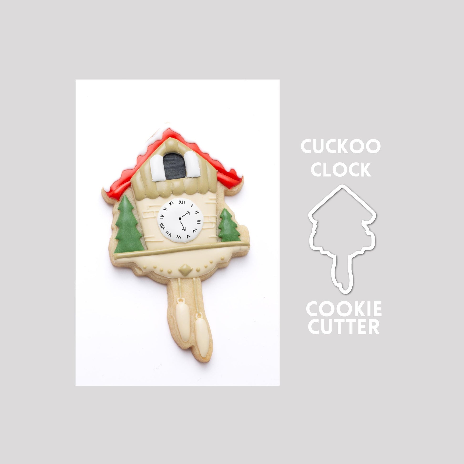Decorated cuckoo clock sugar cookie next to a cuckoo clock cookie cutter outline on a gray background.