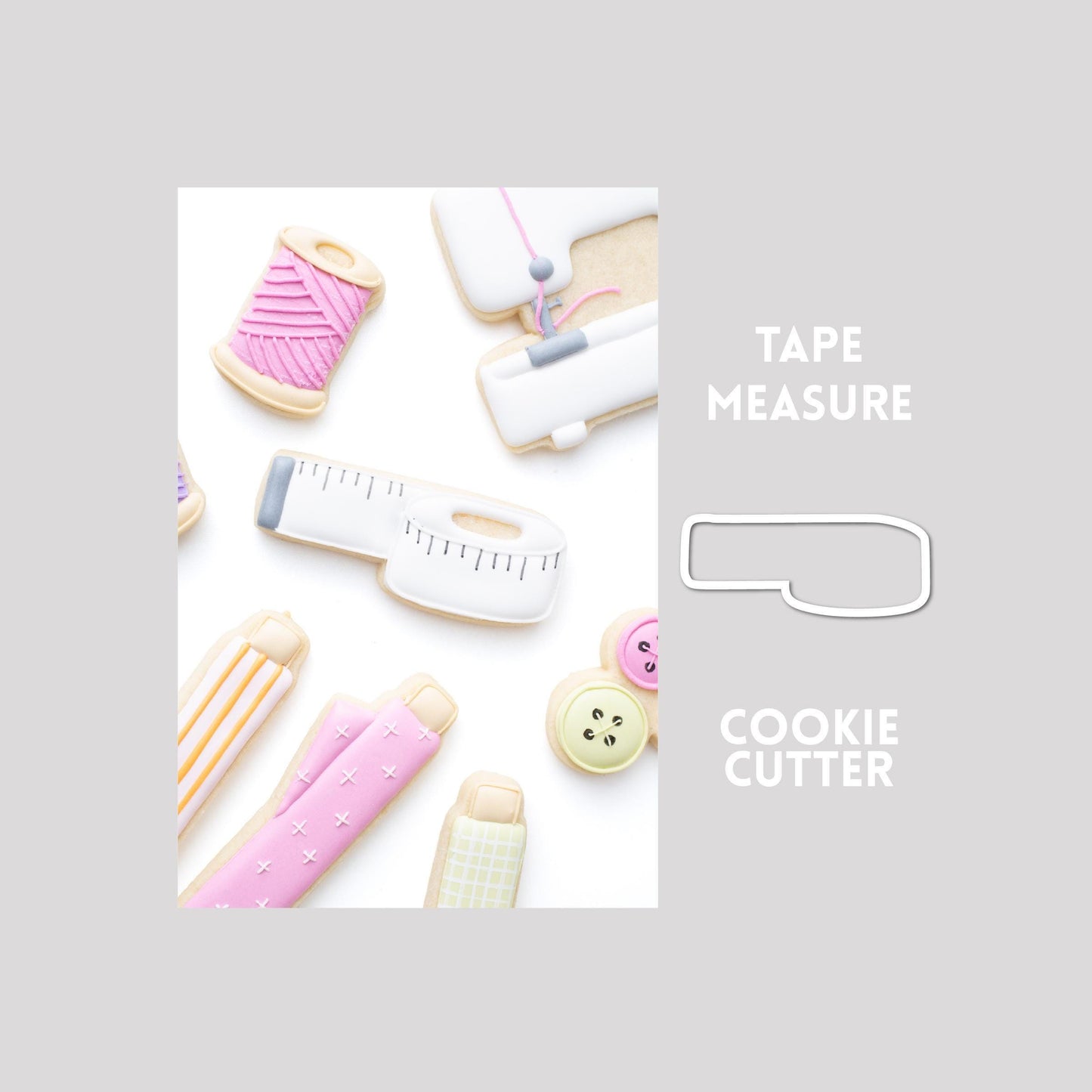 Decorated tape measure sugar cookie next to a tape measure cookie cutter outline on a gray background.