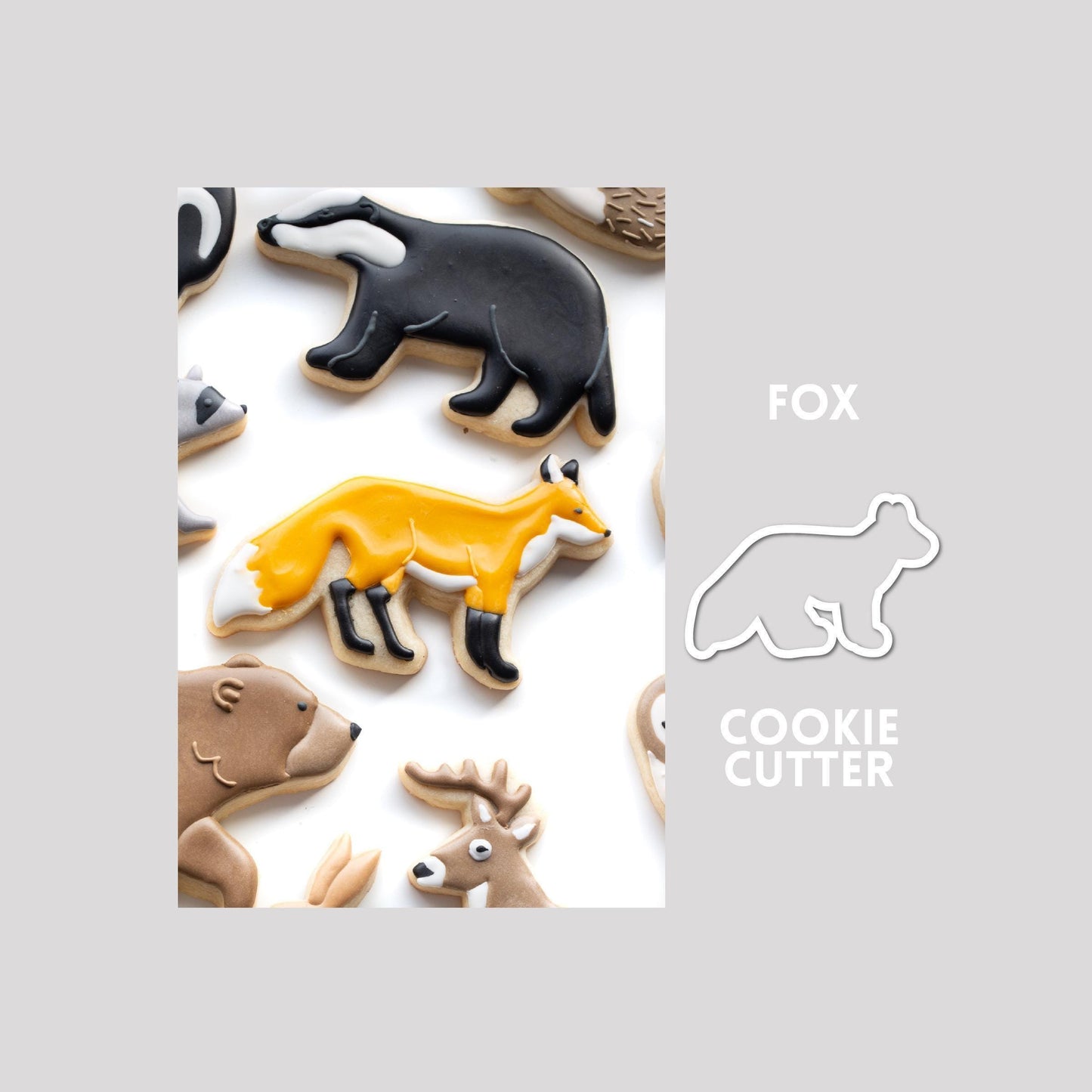 Decorated fox sugar cookie next to a fox cookie cutter outline on a gray background.