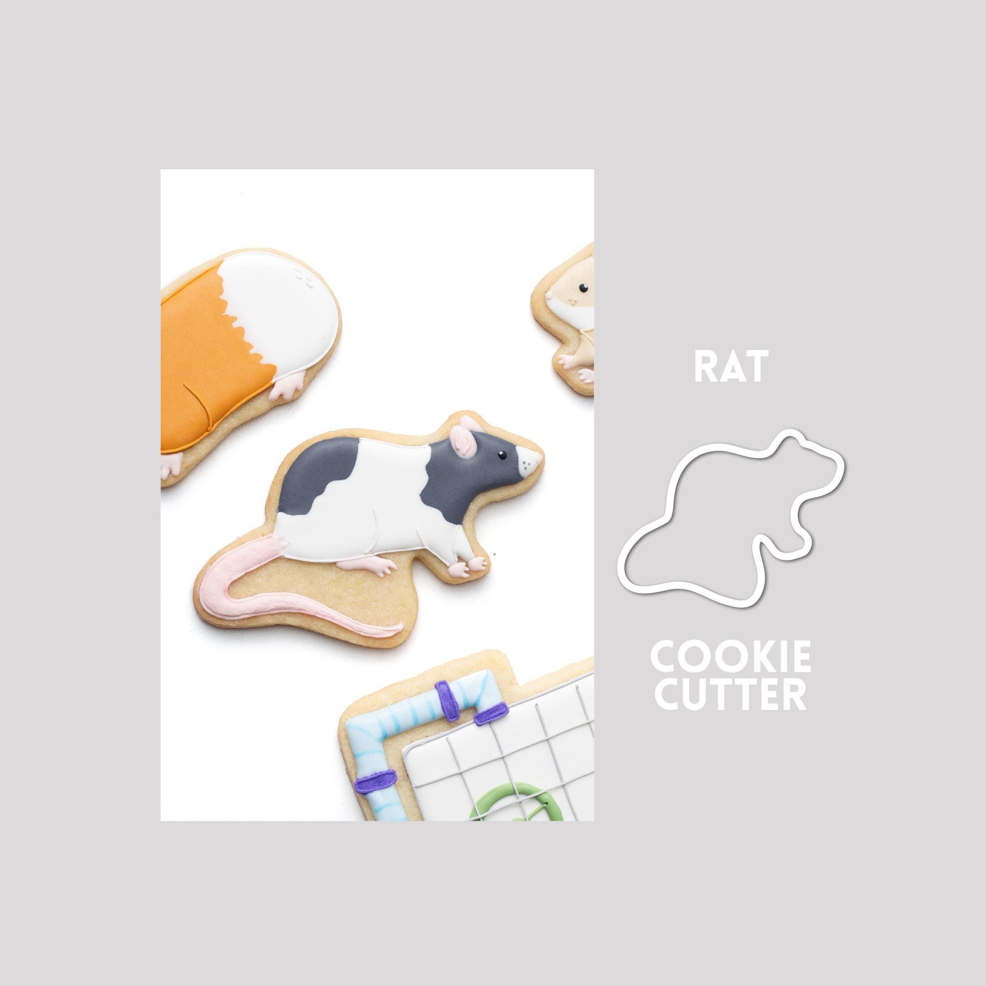 Decorated rat sugar cookie next to a rat cookie cutter outline on a gray background.
