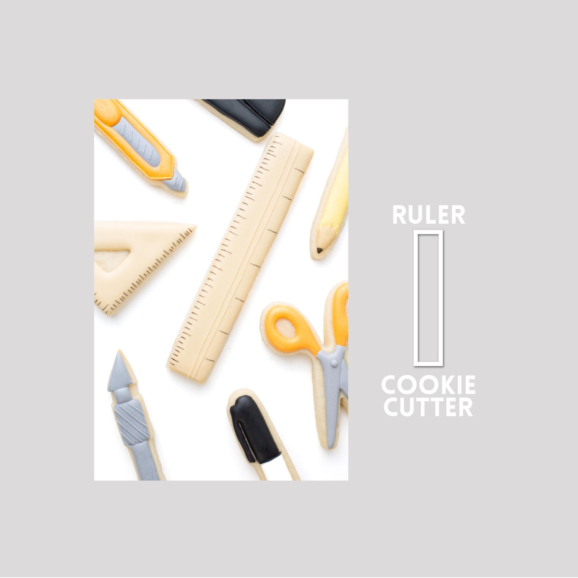 Decorated ruler sugar cookie next to a ruler cookie cutter outline on a gray background.