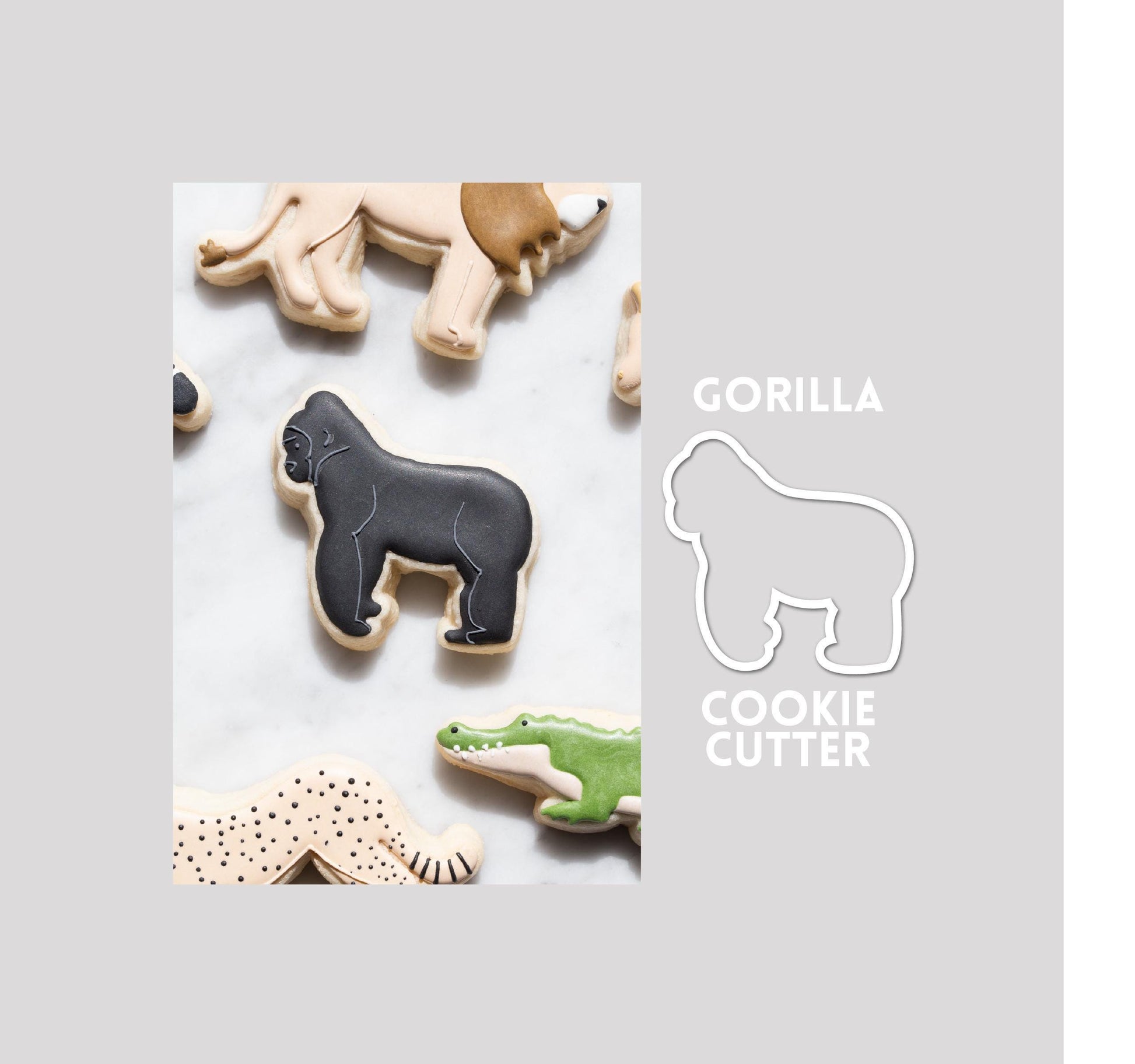 Decorated gorilla sugar cookie next to a gorilla cookie cutter outline on a gray background.