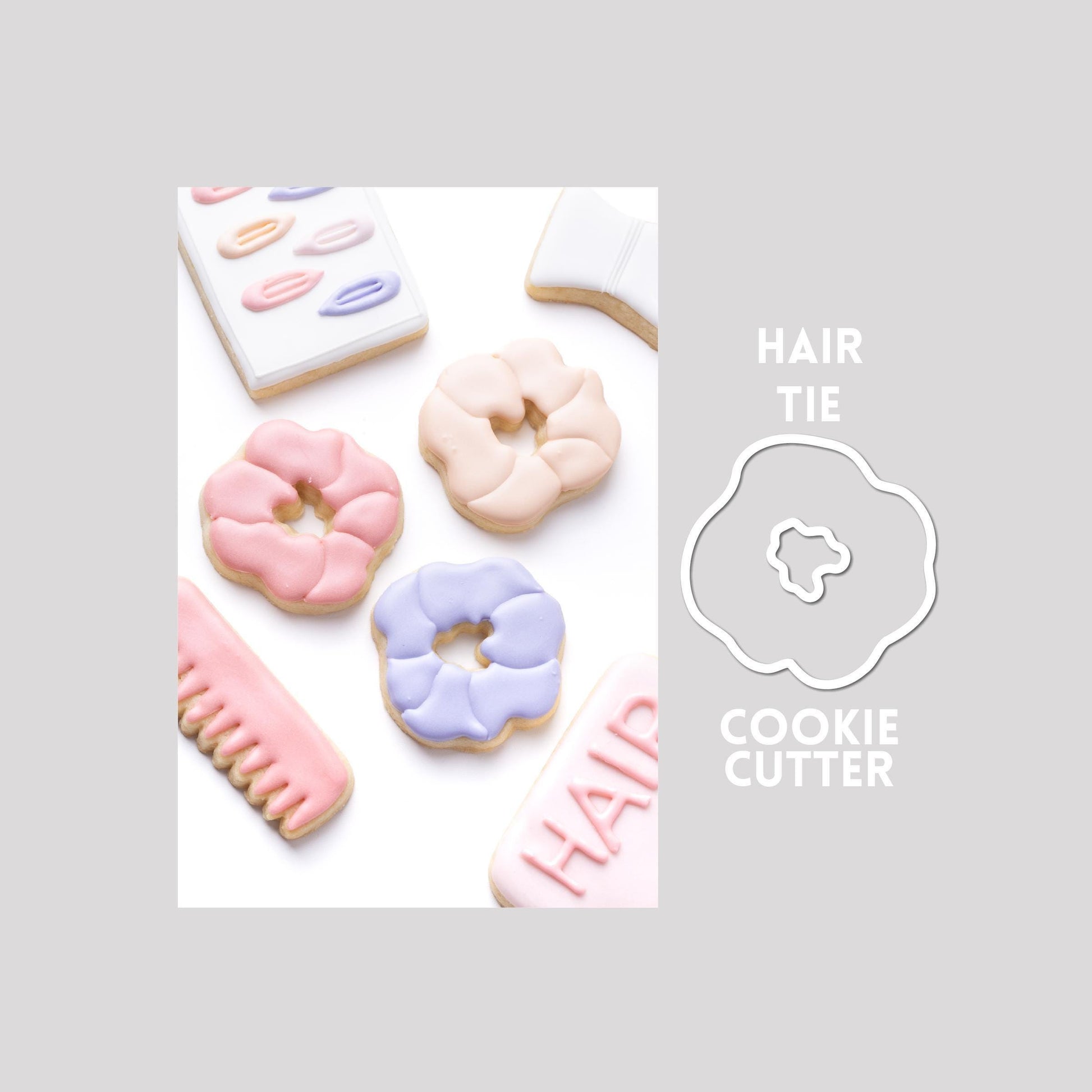 Decorated hair tie sugar cookie next to a hair tie cookie cutter outline on a gray background.