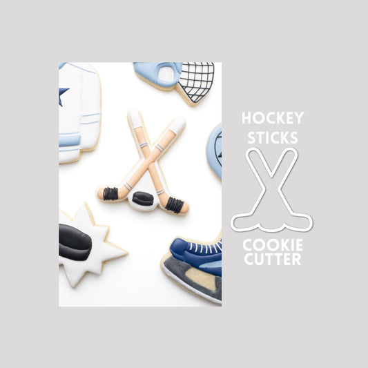 Decorated hockey sticks sugar cookie next to a hockey sticks cookie cutter outline on a gray background.