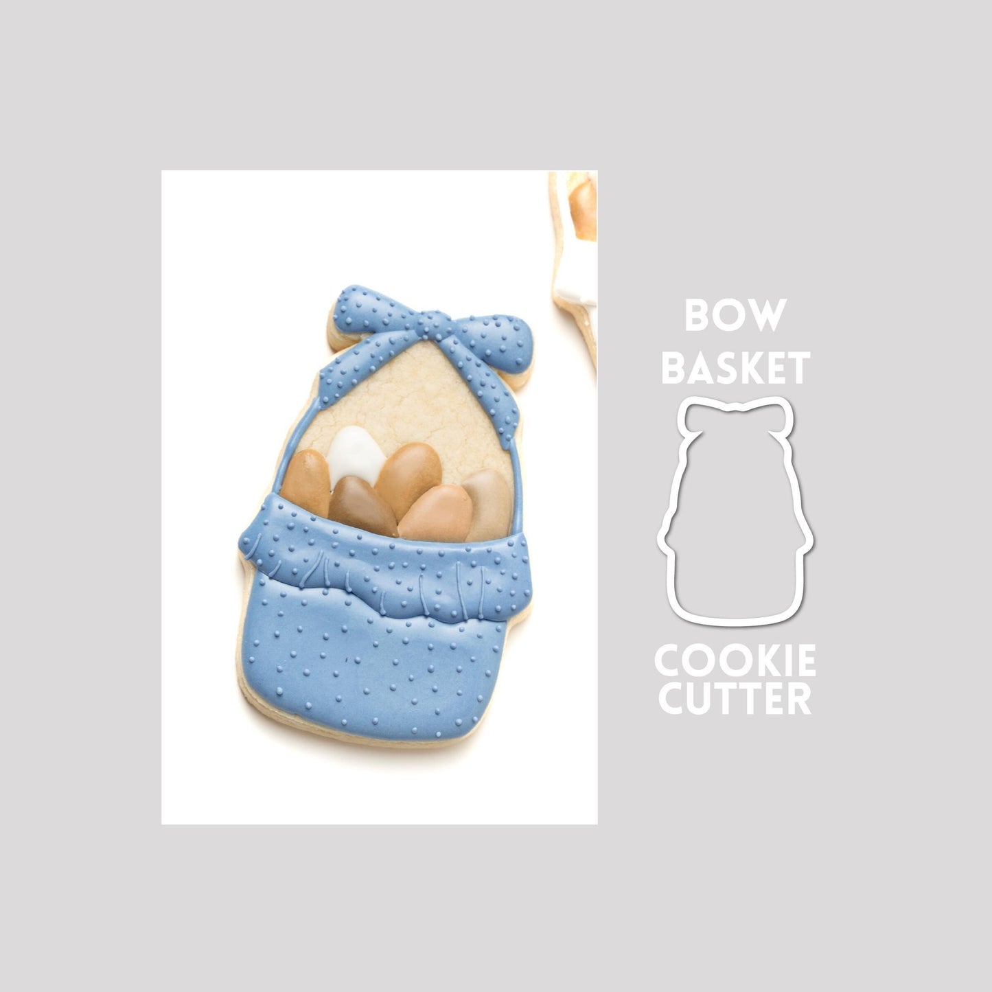 Decorated bow basket sugar cookie next to a bow basket cookie cutter outline on a gray background.