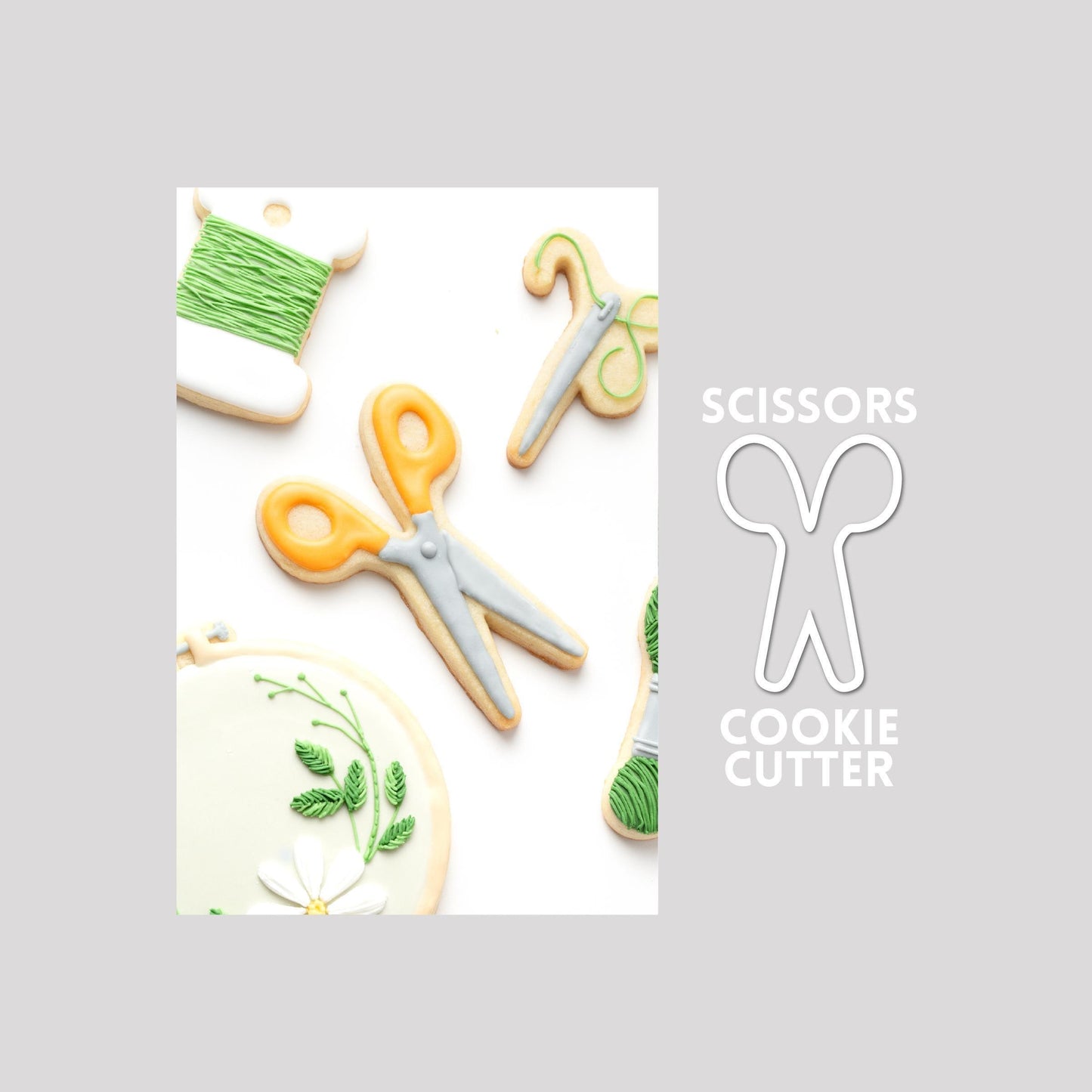 Decorated scissors sugar cookie next to a scissors cookie cutter outline on a gray background.