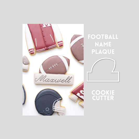 Decorated football name plaque sugar cookie next to a football name plaque cookie cutter outline on a gray background.