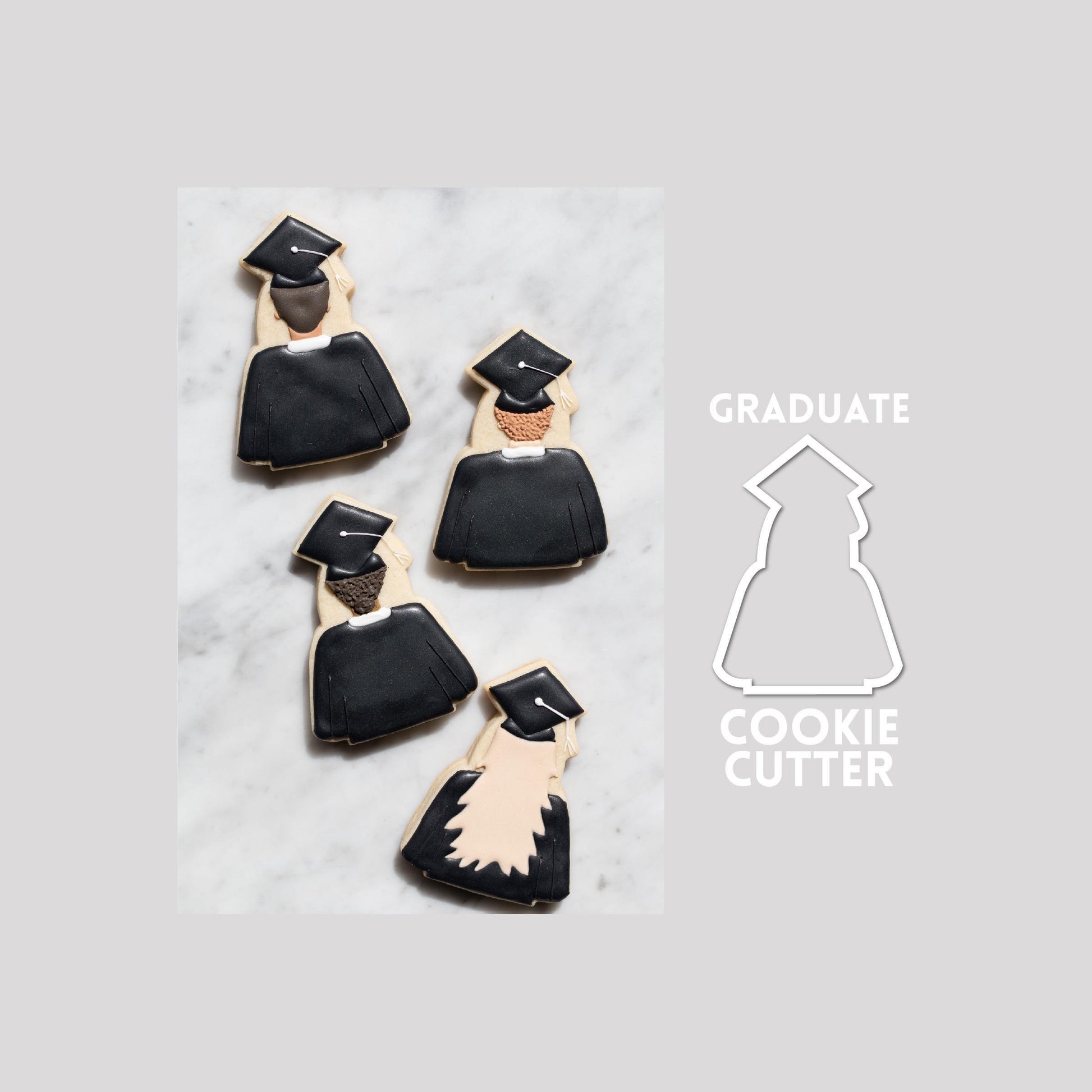 Decorated graduate sugar cookie next to a graduate cookie cutter outline on a gray background.