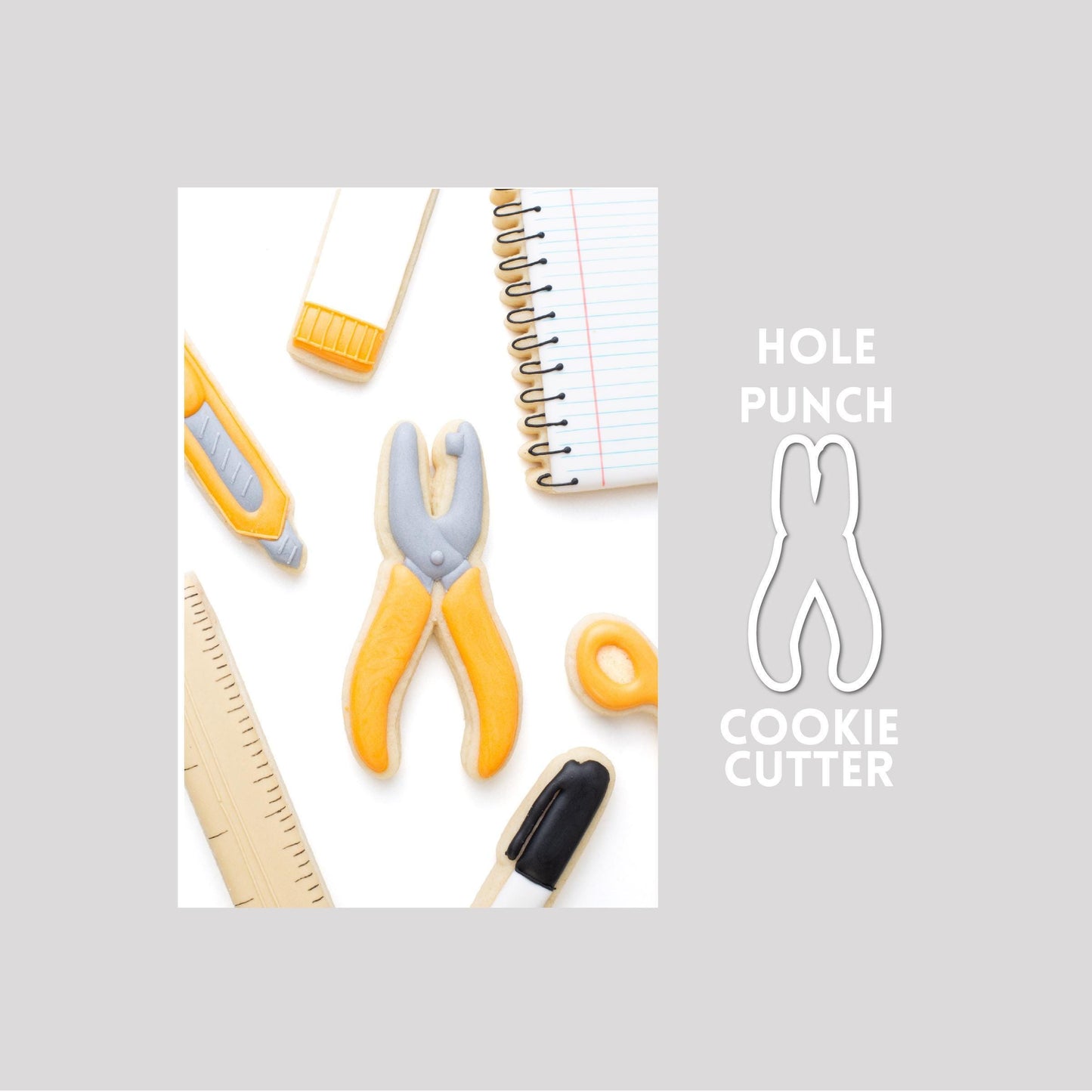 Decorated hole punch sugar cookie next to a hole punch cookie cutter outline on a gray background.