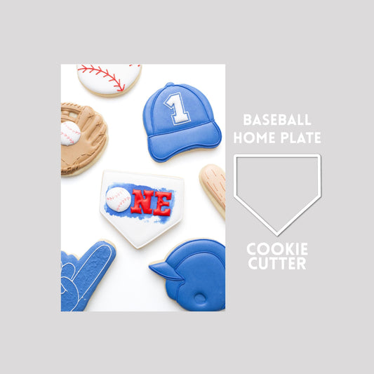 Decorated baseball home plate sugar cookie next to a baseball home plate cookie cutter outline on a gray background.