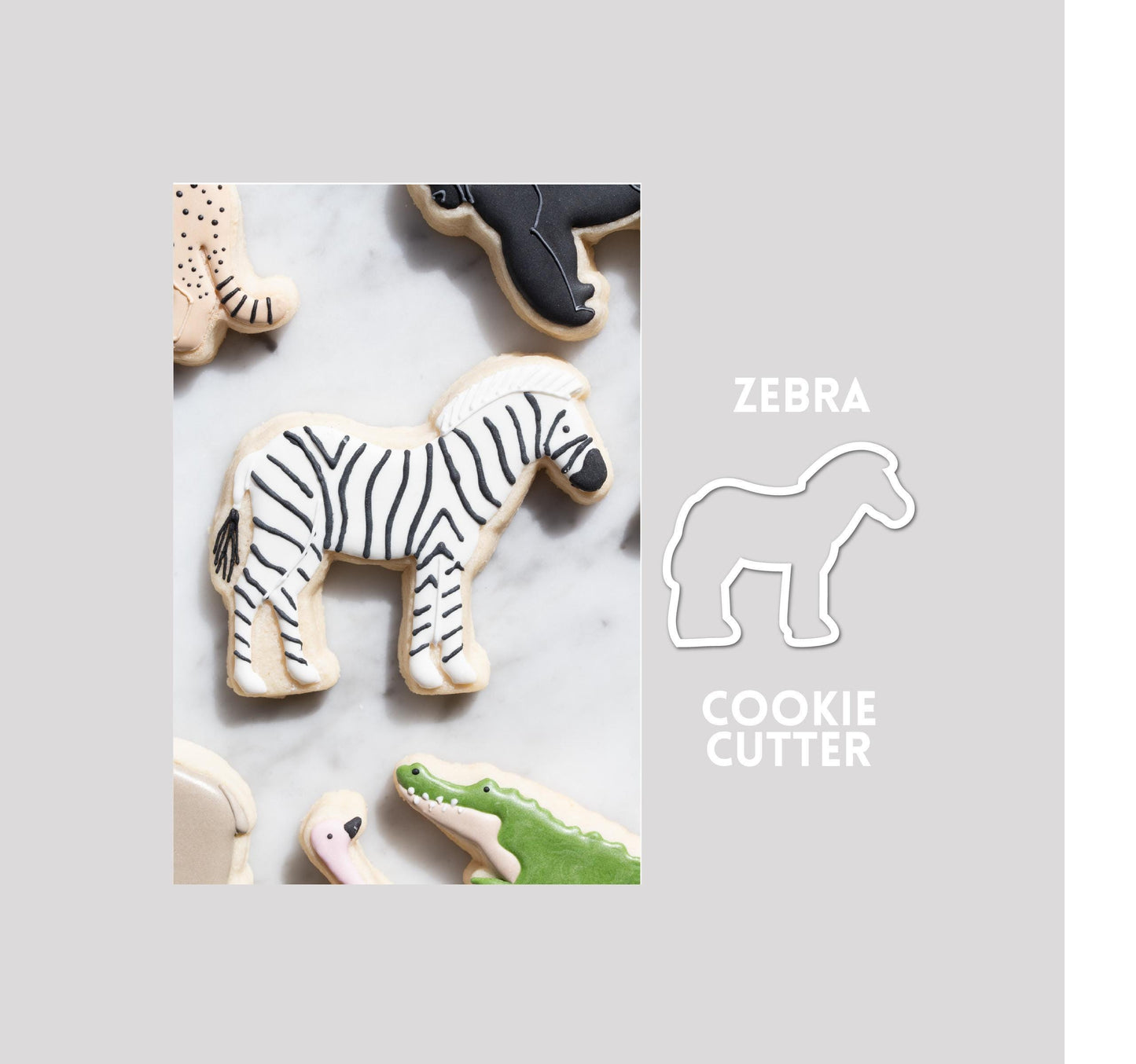 Decorated zebra sugar cookie next to a zebra cookie cutter outline on a gray background.