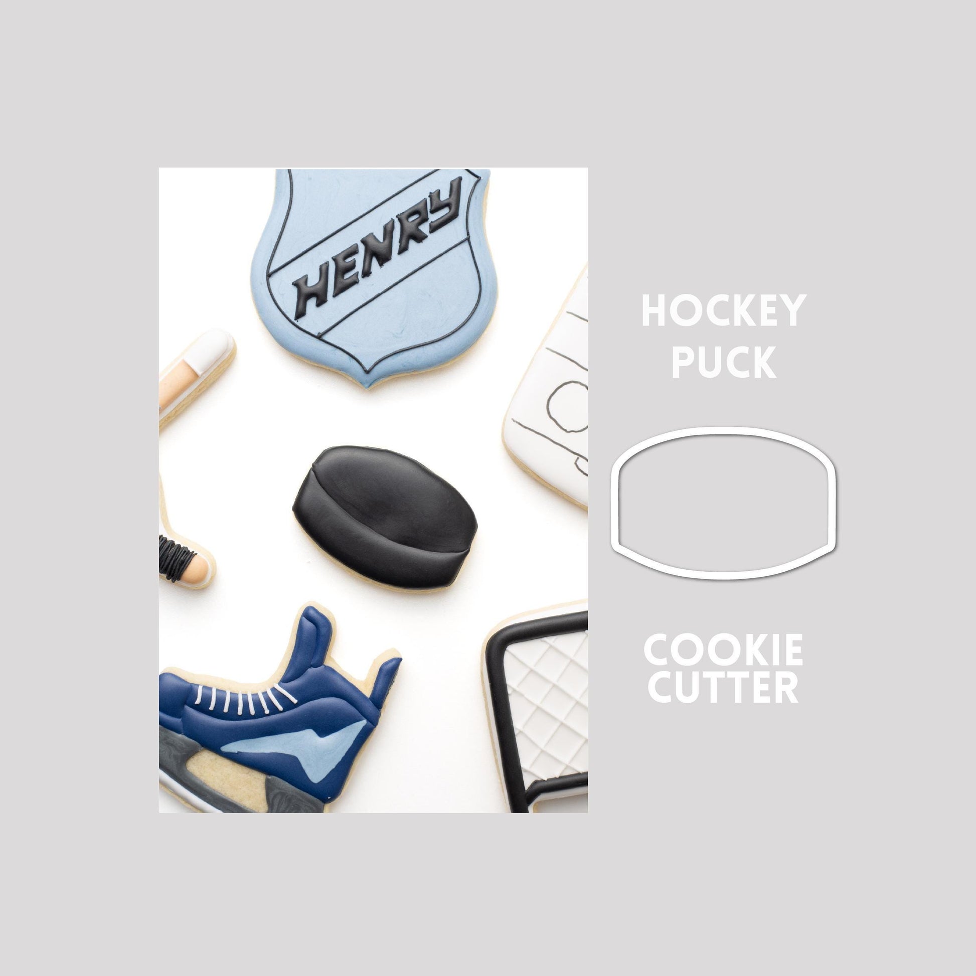 Decorated hockey puck sugar cookie next to a hockey puck cookie cutter outline on a gray background.
