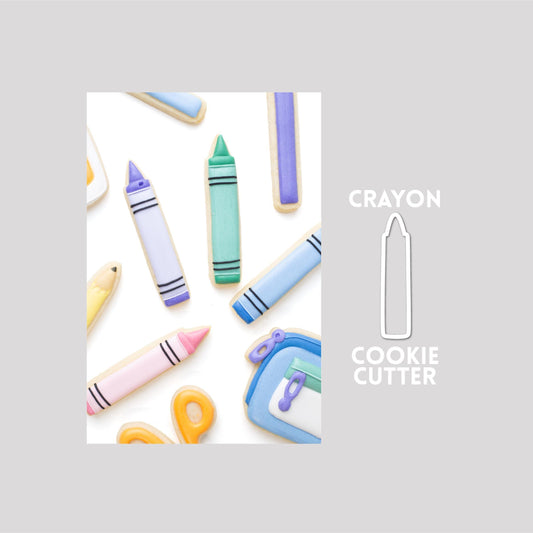 Decorated crayon sugar cookie next to a crayon cookie cutter outline on a gray background.