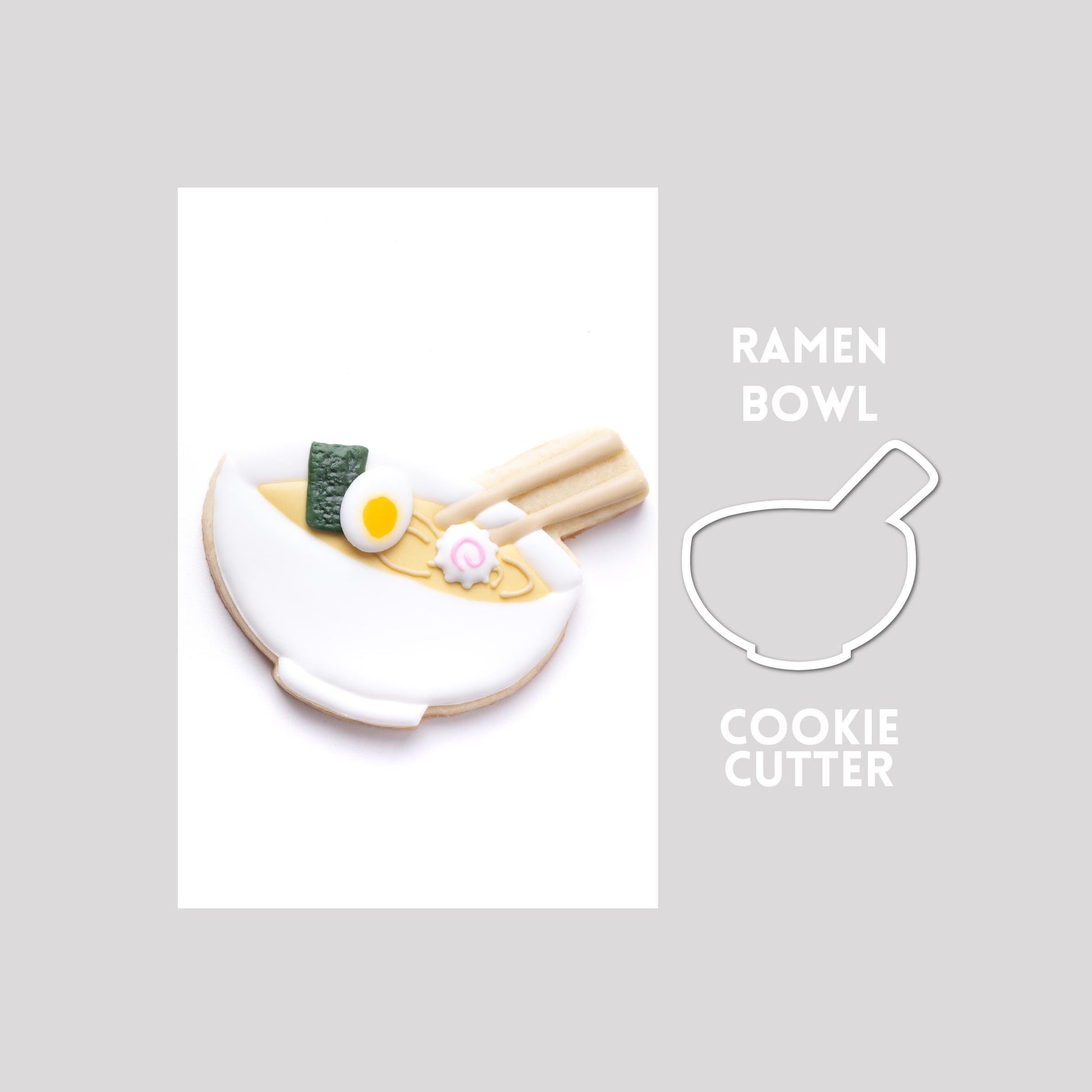 Decorated ramen bowl sugar cookie next to a ramen bowl cookie cutter outline on a gray background.
