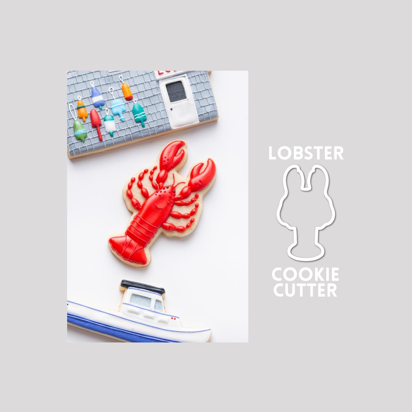 Decorated lobster sugar cookie next to a lobster cookie cutter outline on a gray background.