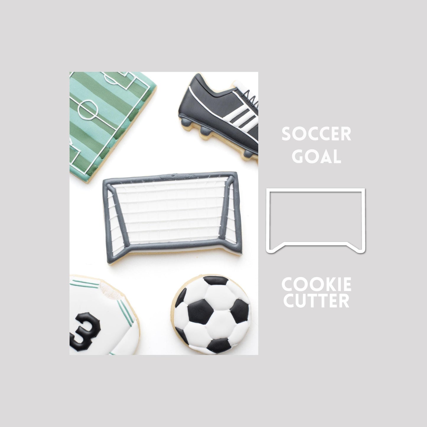 Decorated soccer goal sugar cookie next to a soccer goal cookie cutter outline on a gray background.