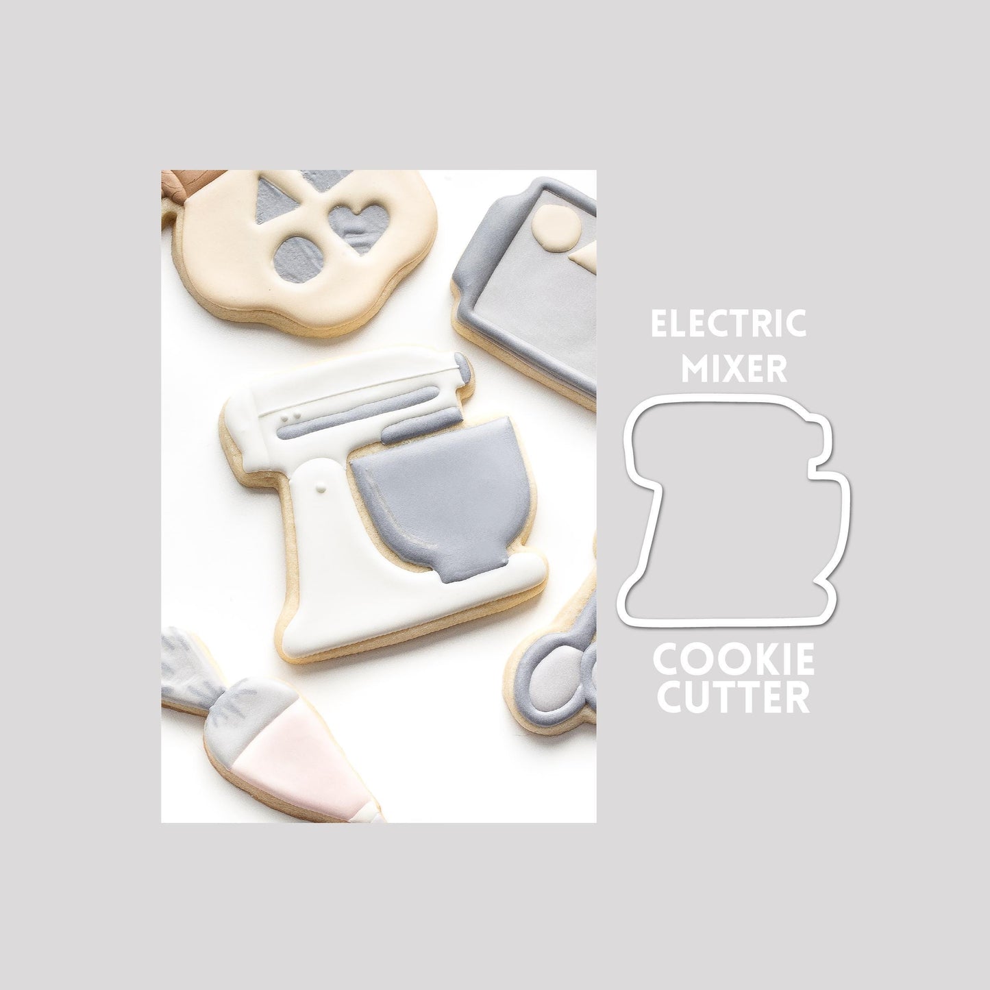 Decorated electric mixer sugar cookie next to a electric mixer cookie cutter outline on a gray background.