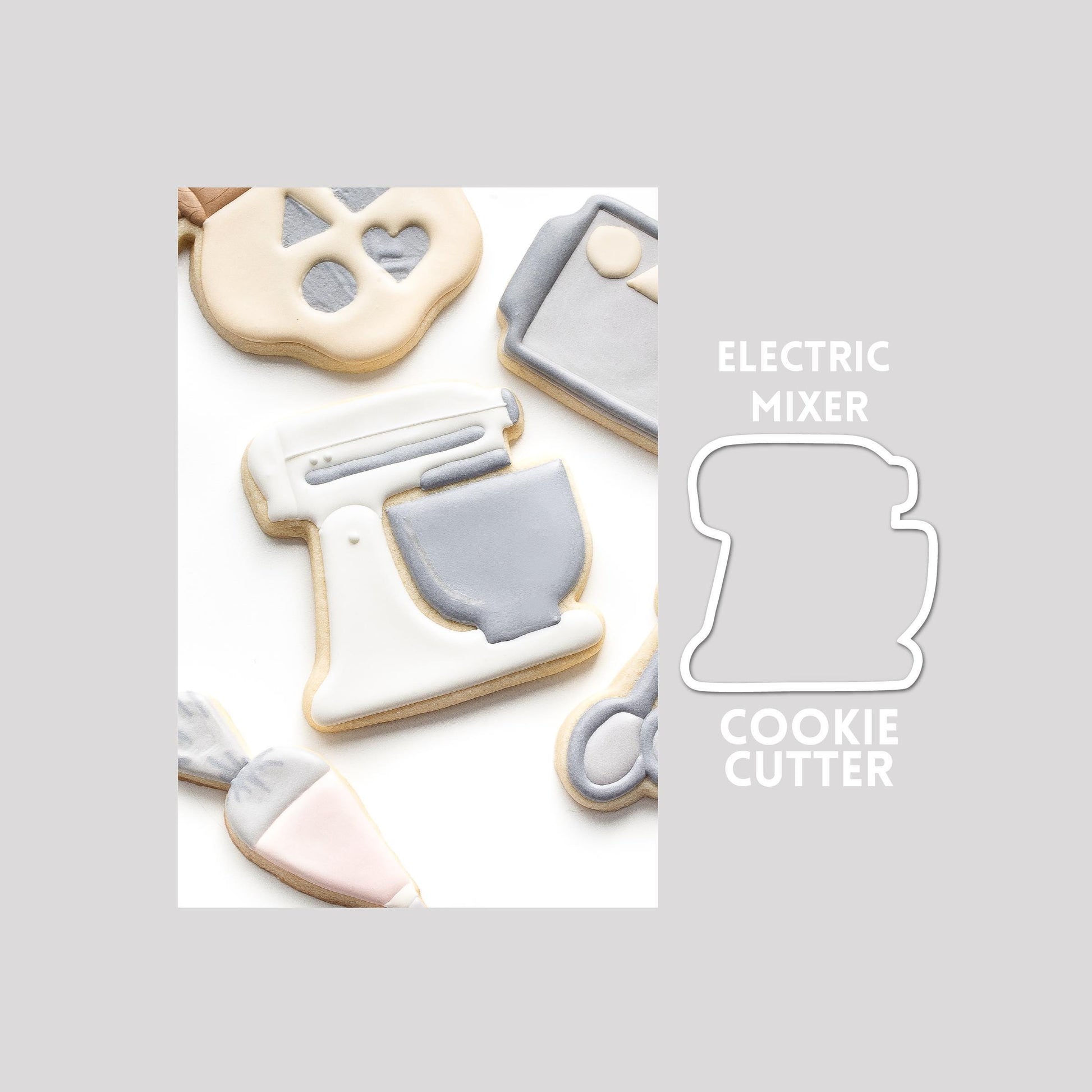 Decorated electric mixer sugar cookie next to a electric mixer cookie cutter outline on a gray background.