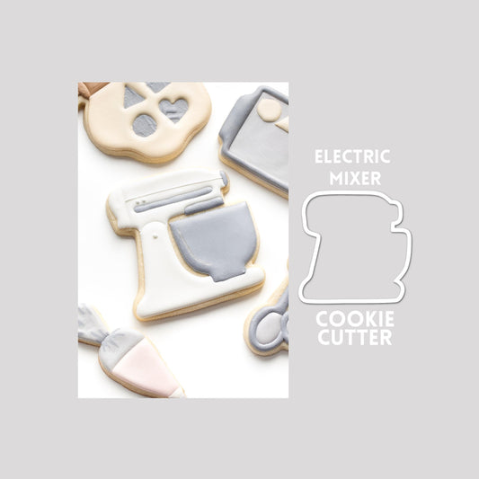 Decorated electric mixer sugar cookie next to a electric mixer cookie cutter outline on a gray background.