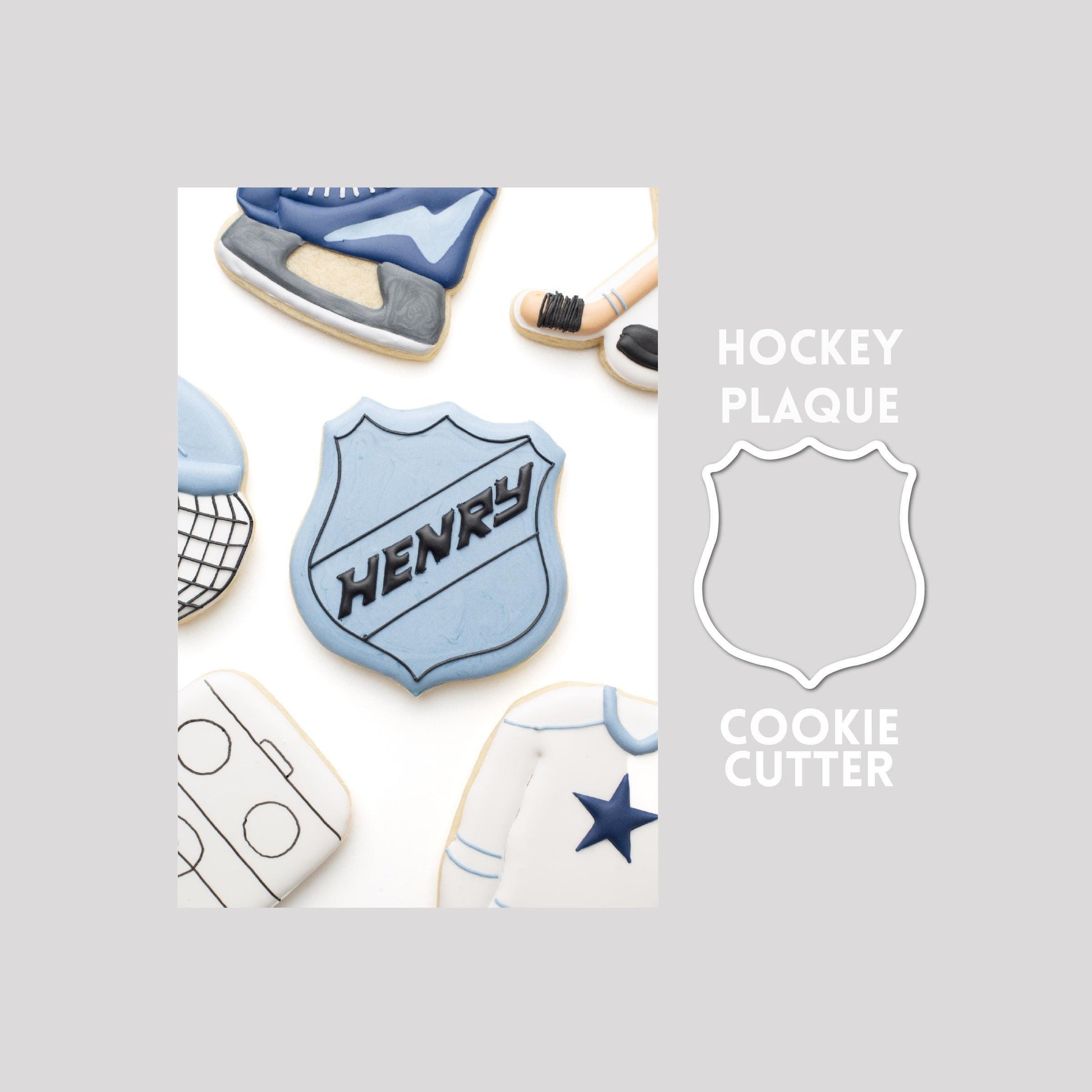 Decorated hockey plaque sugar cookie next to a hockey plaque cookie cutter outline on a gray background.