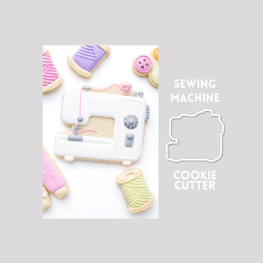 Decorated sewing machine sugar cookie next to a sewing machine cookie cutter outline on a gray background.