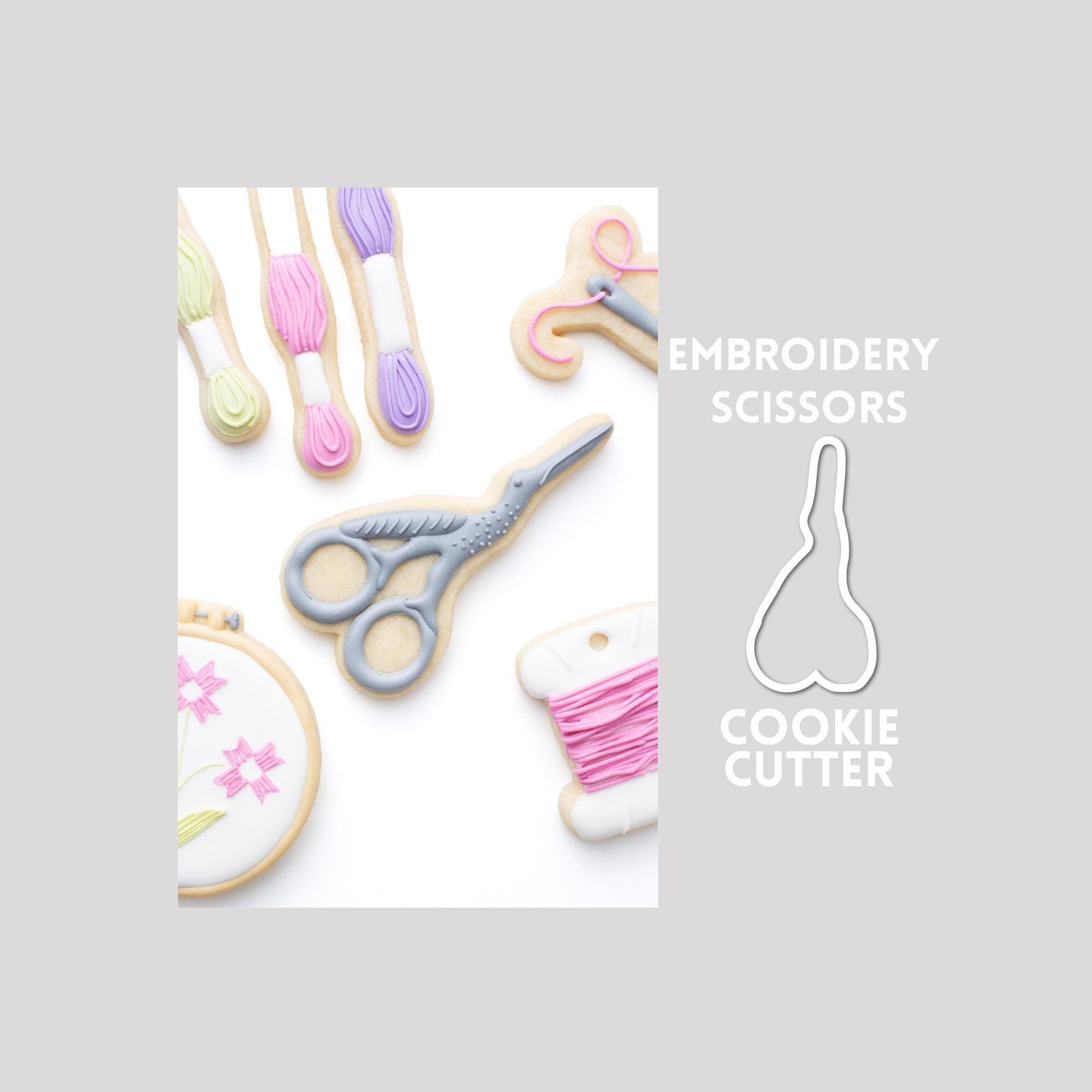 Decorated embroidery scissors sugar cookie next to a embroidery scissors cookie cutter outline on a gray background.